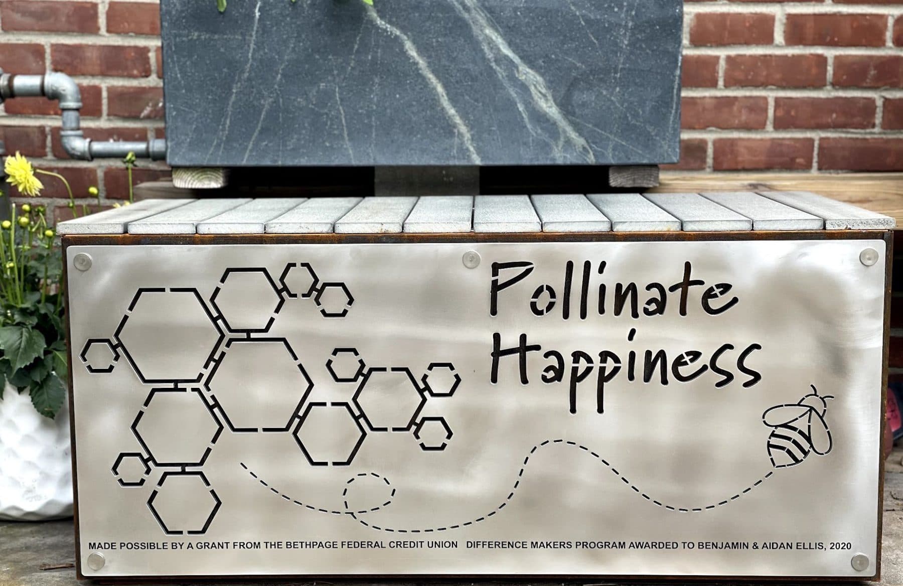 The finished steel Pollinate Happiness sign with honeycomb cutouts